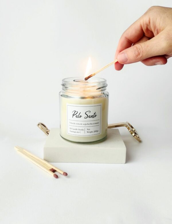 Vela aromática para meditación con fragancia de palo santo, siendo encendida por una mano