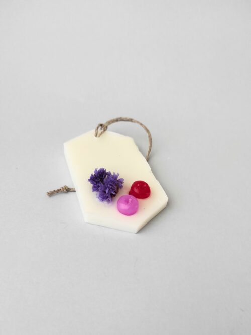 ambientador sólido de cera con una flor seca y dos bolitas de cera de color rosa y roja