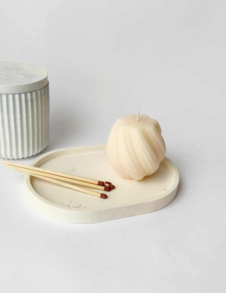 Bandeja minimalista de cemento blanco con una vela y cerillas, ideal para crear un rincón acogedor
