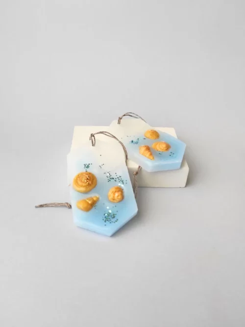 dos ambientadores de cera para armario con fragancia fresca a blue sea. Simulan la orilla del mar con conchas de cera dorada.