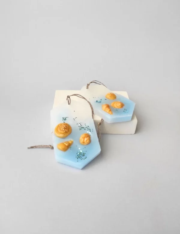 dos ambientadores de cera para armario con fragancia fresca a blue sea. Simulan la orilla del mar con conchas de cera dorada.