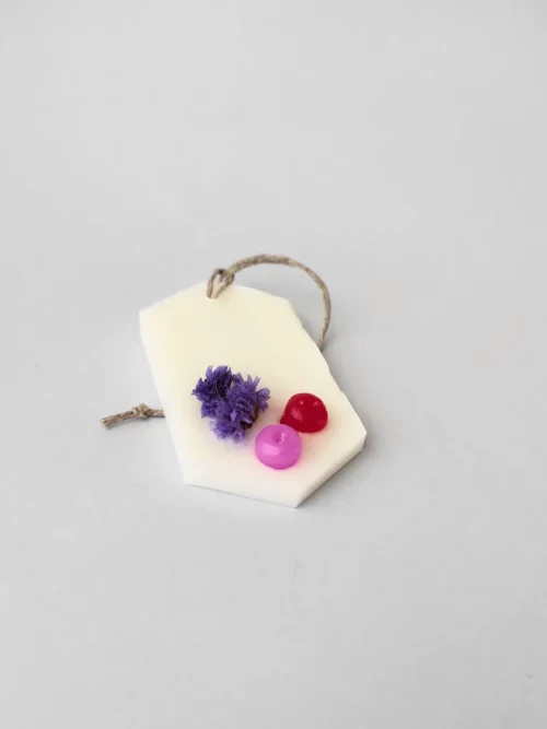 ambientador sólido de cera con una flor seca y dos bolitas de cera de color rosa y roja