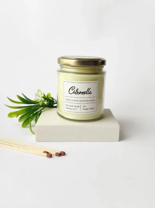 vela aromática citronela, en la parte posterior hay unas hojas de decoración y cerillas al lado