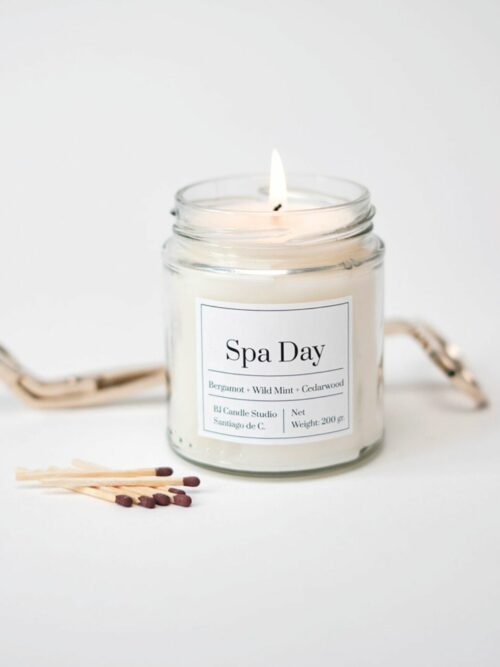 vela vegana hecha a mano con cera de soja. Se llama Spa Day y está encendida con unas cerillas al lado decorando la escena, de estilo minimalista.